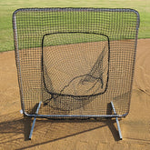 A baseball net positioned on a well-maintained baseball field, surrounded by green grass.